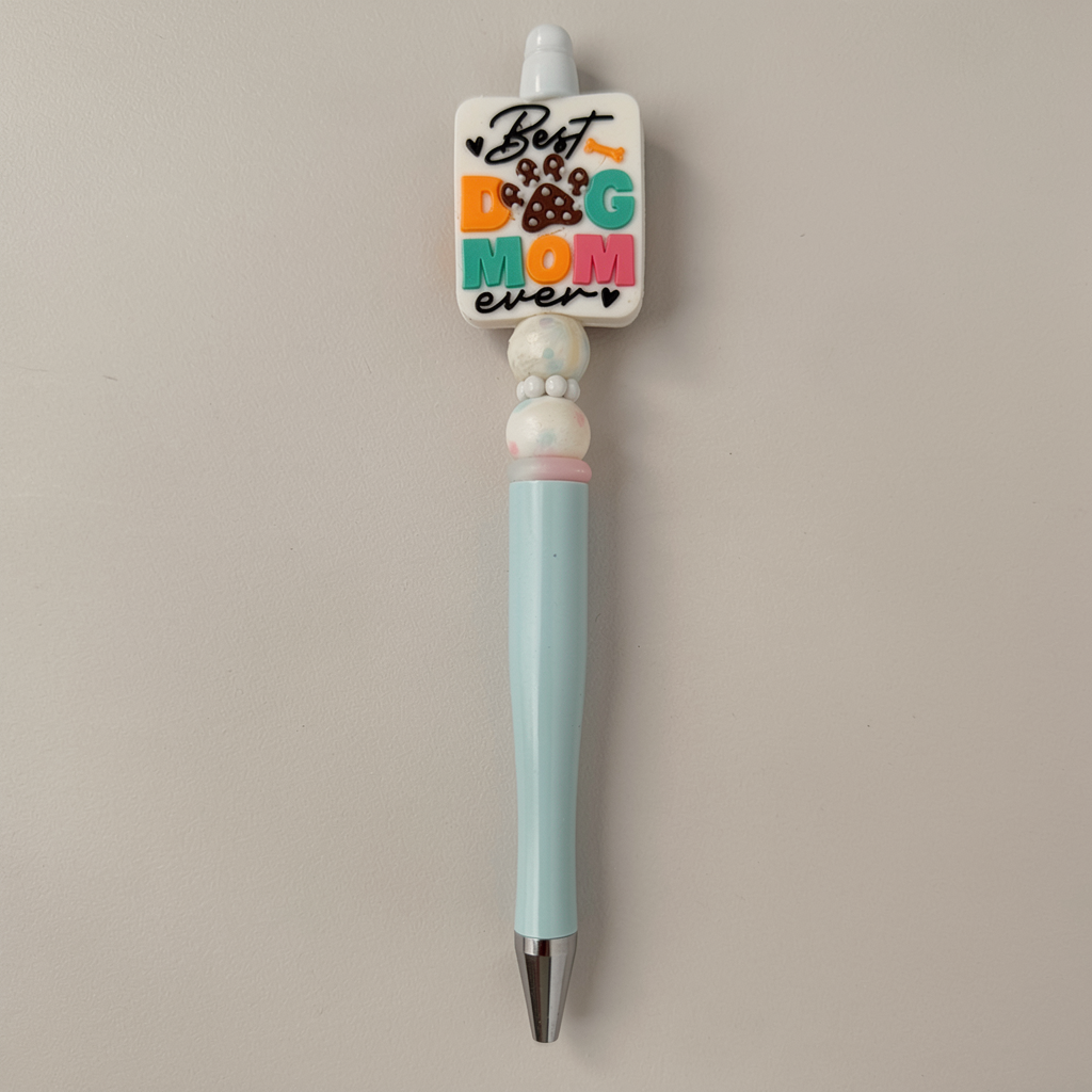Pen with a decorative top that reads 'Best Dog Mom ever' on a beige background