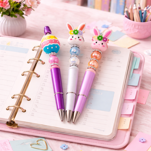 Three decorative pens with rabbit designs on a planner with colorful tabs.