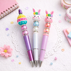 Three decorative pens with rabbit designs on a white surface with stationery items.