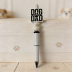 Pen with 'Dog Dad' and paw print design on a wooden surface