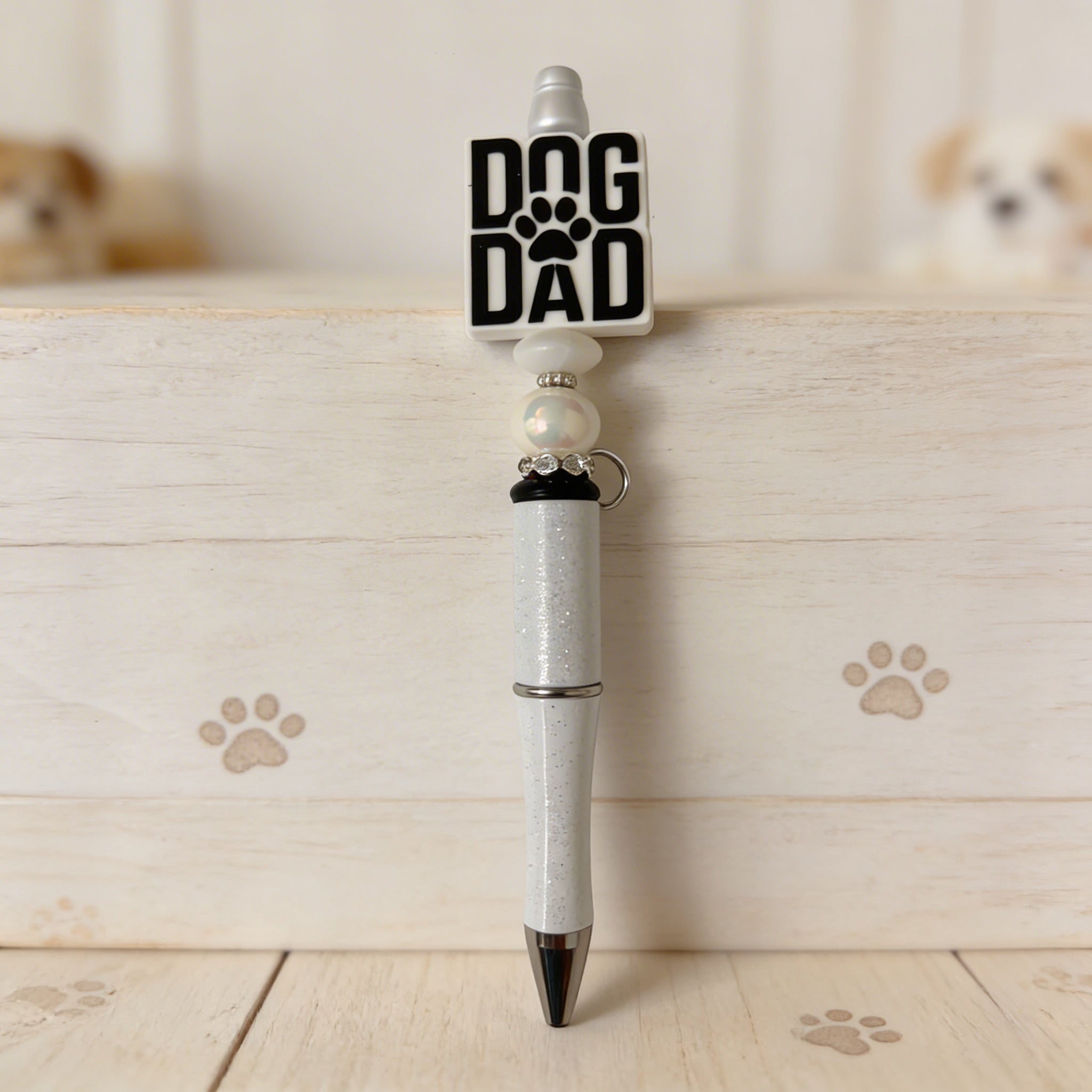 Pen with 'Dog Dad' and paw print design on a wooden surface