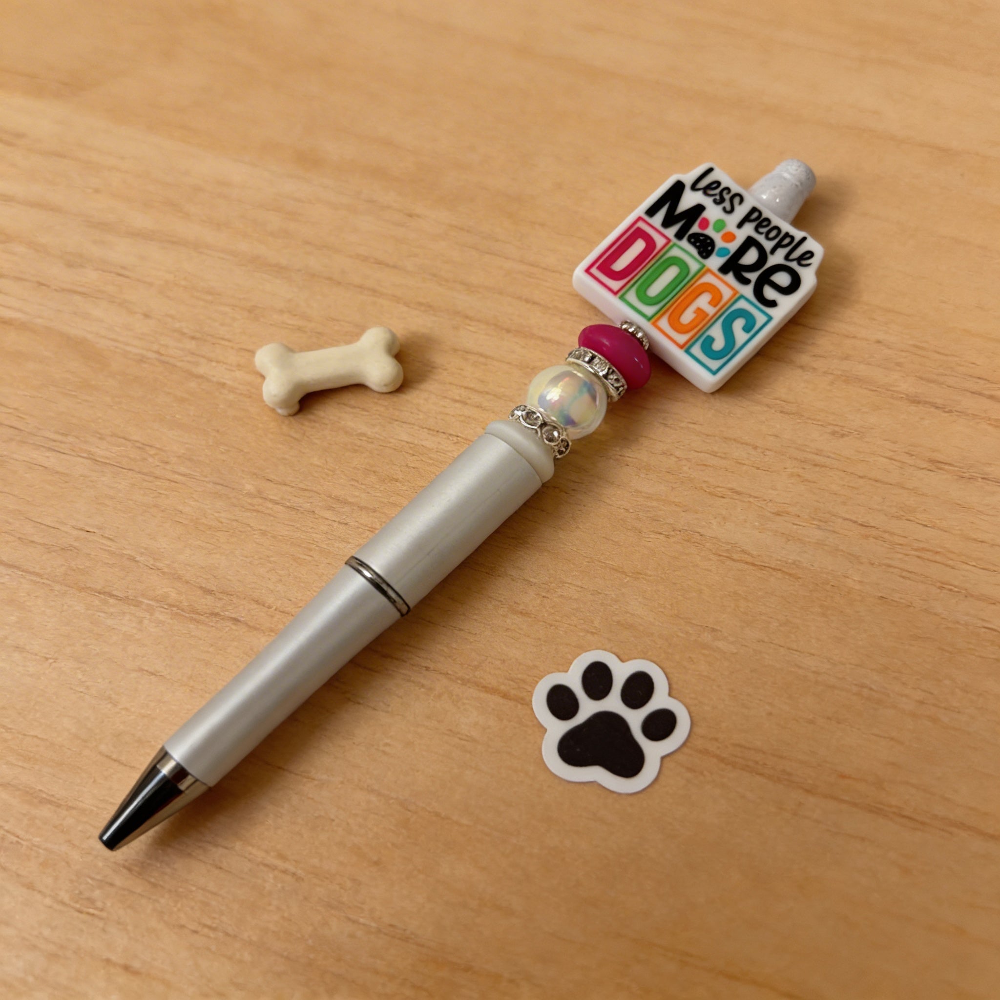 Pen with a decorative top featuring 'More Dogs' text on a wooden surface with a bone and paw print sticker.