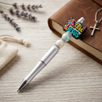 Pen with decorative clip featuring 'TELL YOUR FRIENDS ABOUT JESUS' on a wooden surface with lavender and a book.