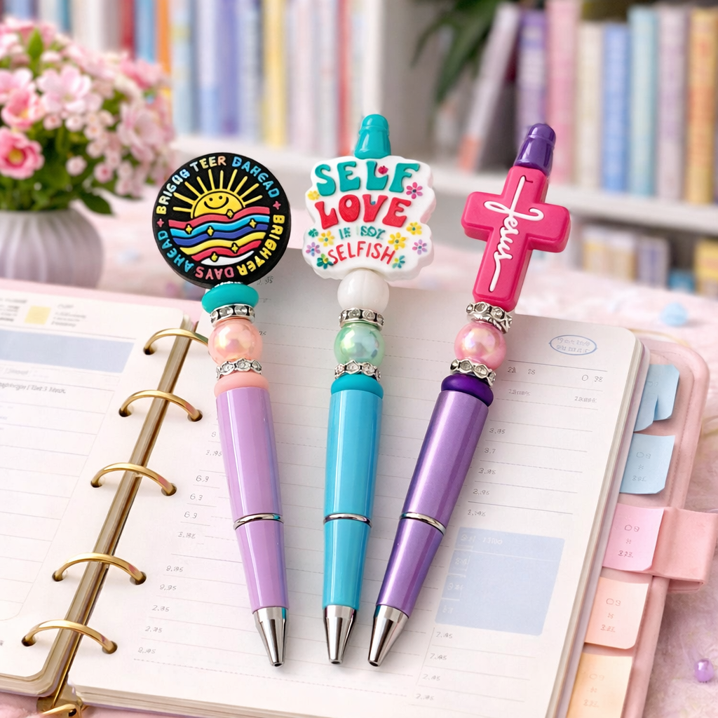 Colorful pens with decorative tips on a planner with a floral and bookshelf background