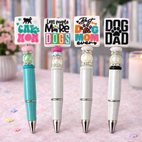 Four decorative pens with humorous text designs on a blurred background